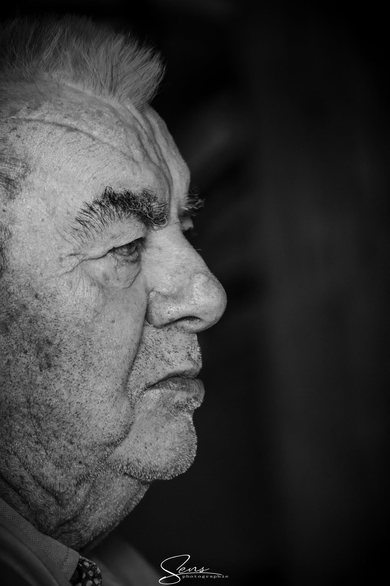 Portrait en noir et blanc d'un homme âgé, de profil, le regard grave