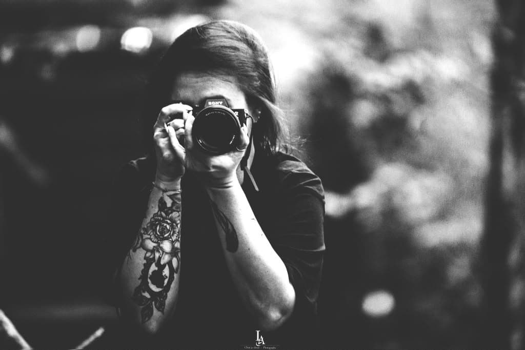 Samantha en noir et blanc, appareil photo en main, dans un sous-bois